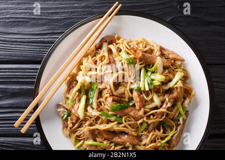 Gebratene Shanghaier Nudeln mit napa Kohl-Grünzwiebeln und Schweinefleisch in einem Teller auf dem Tisch Horizontal von oben Stockfoto