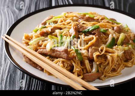 Gebratene Shanghaier Nudeln mit napakohl, grünen Zwiebeln und Schweinefleisch in einem Teller auf dem Tisch umrühren. Horizontal Stockfoto