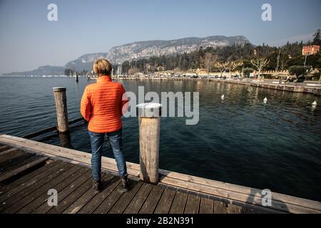 Frau in orangefarbener Jacke am Gardasee, Italien Stockfoto