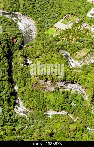 Ein Luftbild zeigt einen sich windenden Fluss, der durch eine dichte, grüne Waldlandschaft schneidet. Der Fluss fließt über felsige Böden und bildet in einigen Abschnitten Stromschnellen. Oben rechts, A Stockfoto