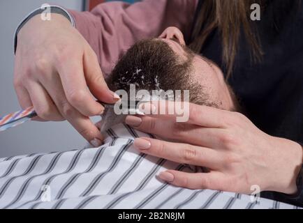 In der Nähe der Haarschnitt und Bart. Eine professionelle Master bereitet einen Kunden Bart zum Schneiden und Rasieren ein Bart. Die Schönheit der Männer. Friseure Stockfoto