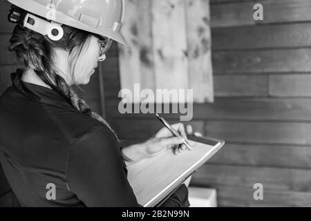 Rückansicht Nahaufnahme der Inspektorin bei der Innenraumluftqualitätskontrolle, da sie mit einer Zwischenablage Notizen in Schwarzweiß mit Kopierraum erstellt. Stockfoto