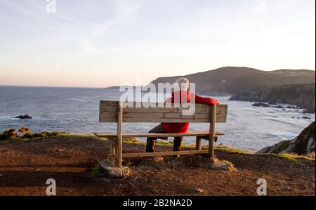 Mann auf einer Wodenbank in Loiba Cliffs, Ortigueira, Spanien Stockfoto