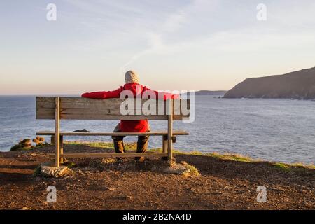 Mann auf einer Wodenbank in Loiba Cliffs, Ortigueira, Spanien Stockfoto