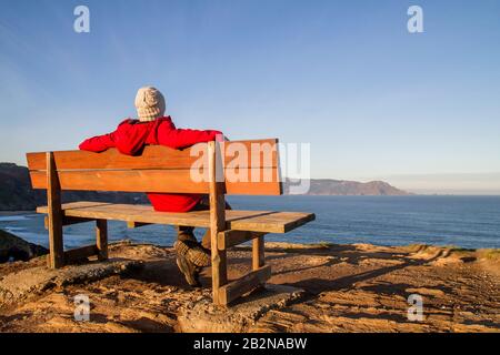 Mann auf einer Wodenbank in Loiba Cliffs, Ortigueira, Spanien Stockfoto