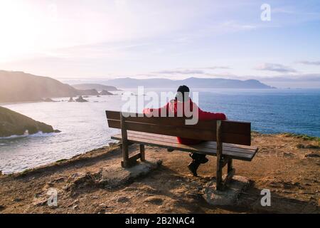 Mann auf einer Wodenbank in Loiba Cliffs, Ortigueira, Spanien Stockfoto