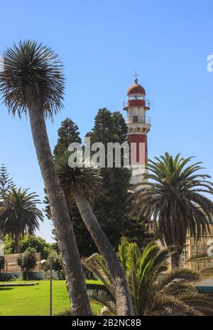 Swakopmund, Namibia - 18. April 2015: Alter deutscher rot-weißer Leuchtturm, der von Palmen umgeben als "Speck" bezeichnet wird Stockfoto