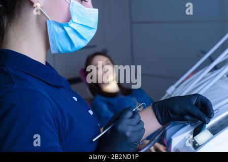 Nahaufnahme eines Zahnarztarztes mit Gegenlicht an Geräten, beim betrachten eines Röntgenbildes eines Zahnes, ist der Patient im Hintergrund nicht fokussiert. Im d Stockfoto