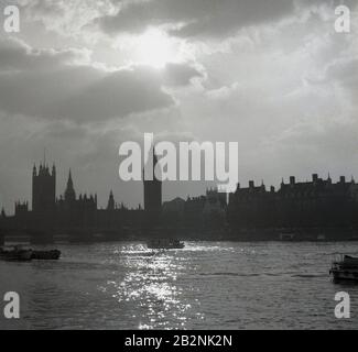 1950er Jahre, historisch, abends und Blick über die Themse mit Blick auf die northbank, mit dem Clock Tower und dem Palace of Westminister, der sich in der Skyline von London, England, Großbritannien abhebt. Stockfoto