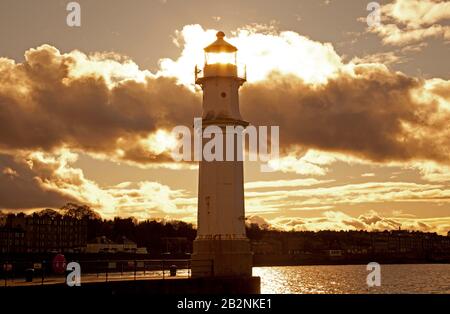 Newhaven Harbour, Leith, Edinburgh, Schottland, Großbritannien. März 2020. Zehn Grad fühlen sich wie acht mit einem lebhaften Wind, der die dramatischen Wolken mittreibt und gelegentlich Regenschauer mit sich bringt. Die am späten Nachmittag positionierte Sonne scheint durch, wo das ursprüngliche Licht in der fernen Vergangenheit glänzen würde. Stockfoto