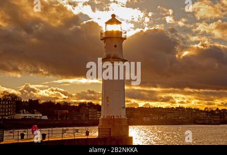 Newhaven Harbour, Leith, Edinburgh, Schottland, Großbritannien. März 2020. Zehn Grad fühlen sich wie acht mit einem lebhaften Wind, der die dramatischen Wolken mittreibt und gelegentlich Regenschauer mit sich bringt. Die am späten Nachmittag positionierte Sonne scheint durch, wo das ursprüngliche Licht in der fernen Vergangenheit glänzen würde. Stockfoto