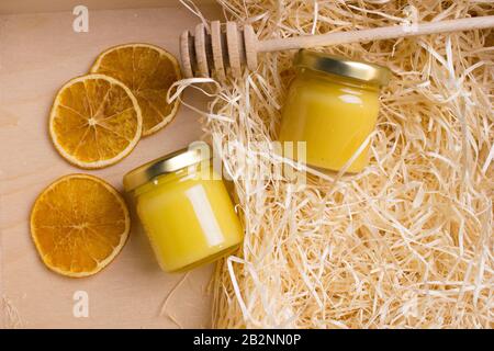 Honig im Glasbecher auf einem Holzboden. Hintergrund mit frischem Honig in klaren Glasgefäßen. Stockfoto