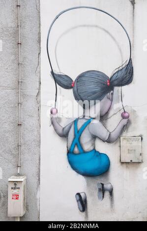 Surreale Straßenkunst EIN junges Mädchen mit einem Springseil springt durch die Wand. Von Graffiti-Künstler bekannt als Seth. Pariser Viertel La Butte aux Cailles. Stockfoto