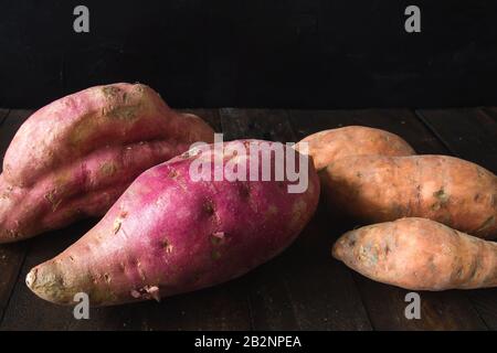 Rohe Süßkartoffeln auf dem rustikalen Küchentisch Stockfoto