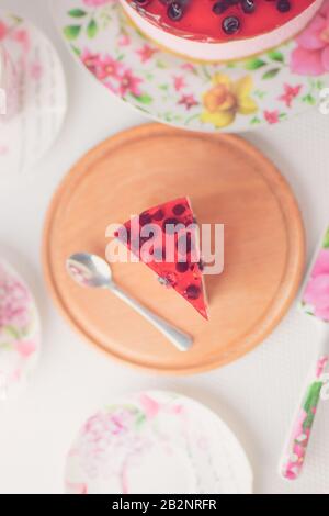 Brombeere Käsekuchen und Löffel auf runder Holztafel. Zwei Tassen für Tee, Untertasse auf weißem Tisch. Stockfoto