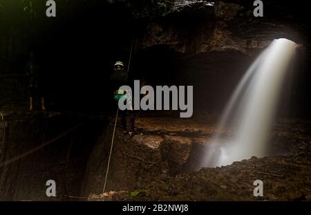 Speläologen In Der Mayei Cavern, Der Höhle, In Der Der Wind Neugeboren Ist (Cueva Donde Nace El Viento) In Der Ecuadorianischen Amazonia-Wasserfall-Eintrag Blured Motion Stockfoto