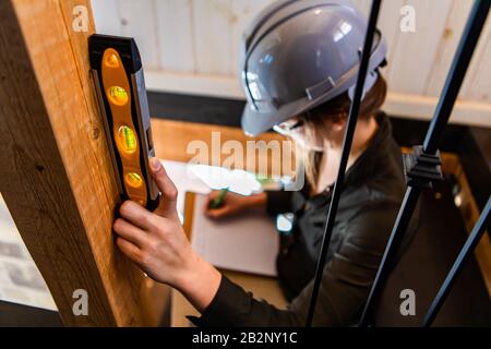 Weibliche Bauinspektorin. Selektive Konzentration der Spirituosenhöhe auf die Hand der Frau nimmt sie bei einer Vorkaufskontrolle Notizen auf ihre Zwischenablage. Stockfoto