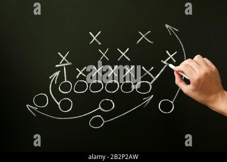 Coach zeichnet American Football oder Rugby Spielbuch, Strategie und Taktik mit Kreide auf der Tafel. Stockfoto