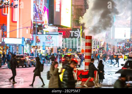 Der Verkehr geht durch und die Menschen überqueren die Avenue unter treibendem Dampf in der regnerischen Nacht am Times Square in Midtown New York City, New York, New York, USA, am 25. Februar 2020. Stockfoto