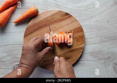 Draufsicht über die handschneidende Karotte auf dem Hackbrett Stockfoto