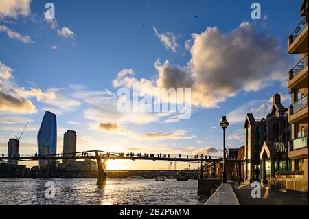 Sonnenuntergang hinter der Millennium Bridge in London, Großbritannien mit dramatischen Wolken. Sie überquert die Themse mit der Blackfriars Bridge und der dahinter liegenden South Bank Stockfoto