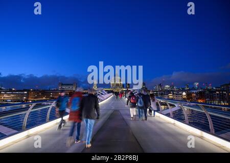 Blick auf die Millennium Bridge und die St Paul's Cathedral in London, Großbritannien. Nicht erkennbare Menschen gehen über die Brücke (Bewegungsunschärfe). Stockfoto