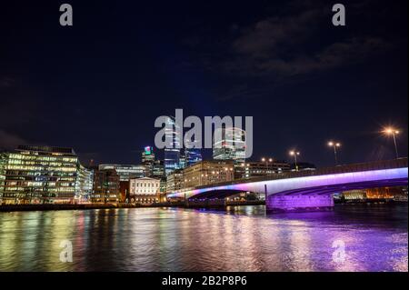 City of London, Großbritannien mit Blick auf die Themse und die London Bridge bei Nacht. Breites Stadtbild mit Wolkenkratzern, Lichtern und dunklem Himmel. London 2020. Stockfoto