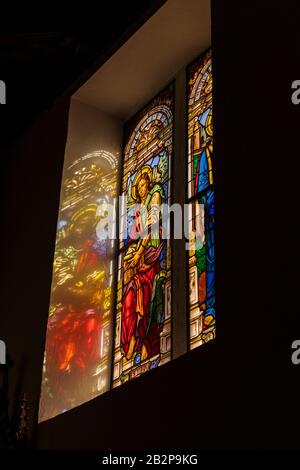 Das Sonnenlicht strömt durch Glasfenster mit Bildern von St. Johannes, San Juan und San Marco in der Kirche Nuestra Senora de Stockfoto