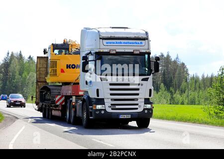 Der weiße Scania-Lkw R500 von KNK Networks transportiert Komatsu-Bagger an einem Sommertag auf dem Highway 4 auf flachem Anhänger. Uurainen, Finnland. Juni 2019. Stockfoto