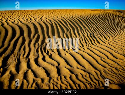 Farbbild in der Dämmerung aufgenommen, abstrakte Ansicht von Wellen von Sand Muster durch die Wüste, Stockfoto