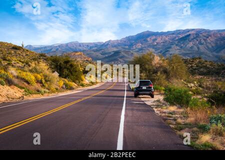 Ein schwarzes Sportwagen, das auf der Seite einer Straße in Arizona mit Wüste und Bergen um sie herum geparkt ist. Stockfoto