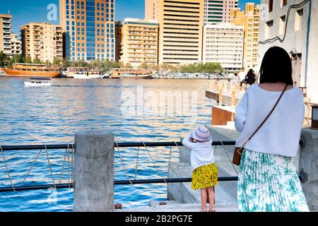 Rückansicht von Mutter und Tochter mit Blick über das Wasser auf Dubai Creek VAE. Stockfoto