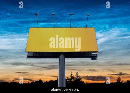 Leeres Billboard mit Kopierbereich, umgeben von farbenfrohem Himmel bei Sonnenuntergang. Große leere Vorlage, Werbefläche Stockfoto