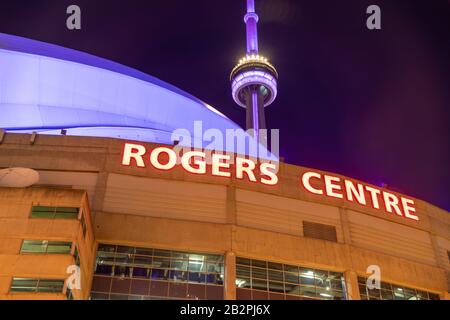 Rogers Centre Schild an der Spitze des berühmten Sportstadions, mit dem CN Tower im Hintergrund oben. Stockfoto