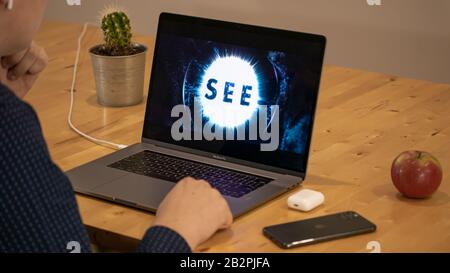Mann sitzt auf einem Deck beim Ansehen der beliebten Apple TV + Show, siehe auf einem MacBook Pro. Stockfoto
