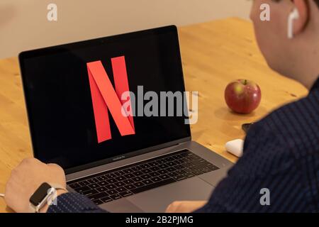 Mann sitzt auf einem Deck Netflix auf einem MacBook Pro beobachten. Stockfoto