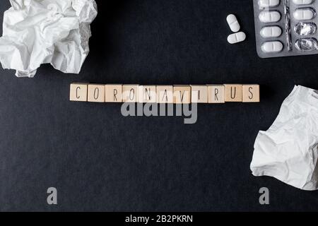 Coronavirus Auf Holzwürfeln mit medizinischen Pillen und Gewebepapieren für Convid-19-Virus, Draufsicht schwarzer Hintergrund Stockfoto