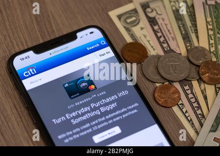 Citigroup Logo auf der Website auf einem Smartphone neben einem Haufen von amerikanischen Bargeld und Wechselgeld auf einem Schreibtisch. Stockfoto