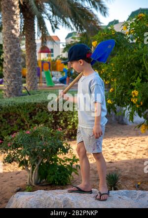 5 Jahre alter Junge, der auf dem Felsen im Garten/Spielplatz steht Stockfoto