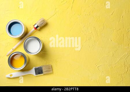 Farbdosen und Bürsten auf gelbem Hintergrund, Draufsicht Stockfoto