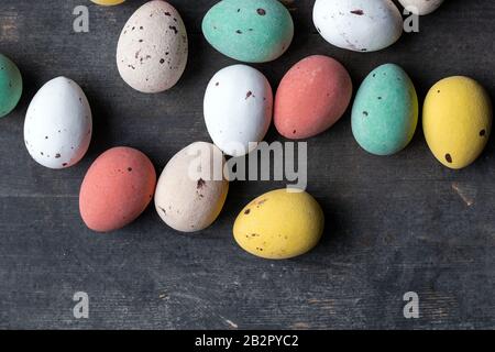 Gefärbte, bunte ostereier auf einem alten Holzhintergrund, weiche Pastelle modernes Design Stockfoto