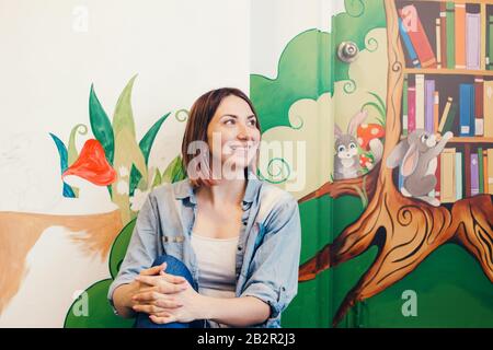 Kaukasische Künstlerin erholt sich, nachdem sie in der Wohnung oder in der Schule Wandbilder mit Acrylfarben in Innenräumen gemalt hat. Kreatives Hobby und freel Stockfoto