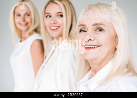 Selektiver Fokus der drei Generationen blonden Frauen isoliert auf Grau Stockfoto