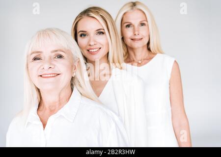 Selektiver Fokus der attraktiven, auf Grau isolierten Blondinen der drei Generationen Stockfoto