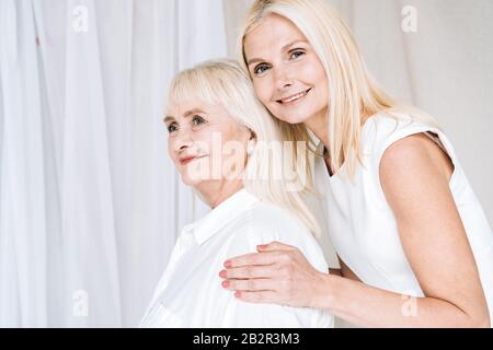 Elegante, blonde, reife Tochter, die die ältere Mutter umarmt Stockfoto