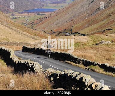 Ein Lone Radfahrer, Der Den Kirkstone Pass An einem hellen Wintertag Besteigen kann, Lake District National Park, Cumbria, England. Großbritannien Stockfoto