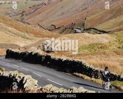 Ein Lone Radfahrer, Der Den Kirkstone Pass An einem hellen Wintertag Besteigen kann, Lake District National Park, Cumbria, England. Großbritannien Stockfoto