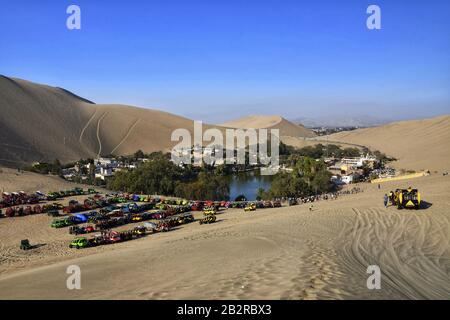 ICA, PERU - 08. September 2019: Weitwinkelaufnahme der Oase Huacachina an einem sonnigen Tag in der Nähe von Ica mit den Buggies und Unes im Hintergrund. Stockfoto