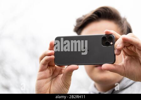 Mann, der an einem hellen Tag ein Foto mit dem iPhone 11 Pro Max draußen aufnahm. Stockfoto