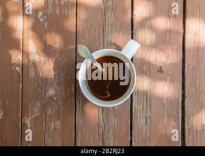 Tasse Kaffee am Tisch in den Strahlen der Sonne am Morgen Stockfoto